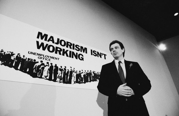 British Labour Party politician and Shadow Secretary of State for Employment Tony Blair at a press conference during the General Election campaign, 24th February 1992. Behind him is a poster showing a queue of unemployed workers with the slogan 'Majorism Isn't Working' - a response to a previous Conservative party poster, which read 'Labour Isn't Working'. (Photo by Peter Macdiarmid/Getty Images)