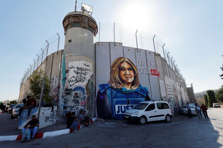 Οι Παλαιστίνιοι κάθονται μπροστά σε μια τοιχογραφία που απεικονίζει τη δολοφονημένη Παλαιστινοαμερικανίδα δημοσιογράφο Shireen Abu Akleh 