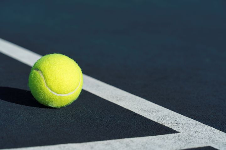 A close up of a tennis ball near the court's boundary line