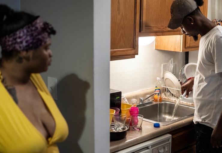 Jamiya Williams (left) watches as her fiance, Terrence Carter (right), pours bleach into the water before washing dishes on Sept. 1 in response to the water crisis in Jackson, Mississippi.