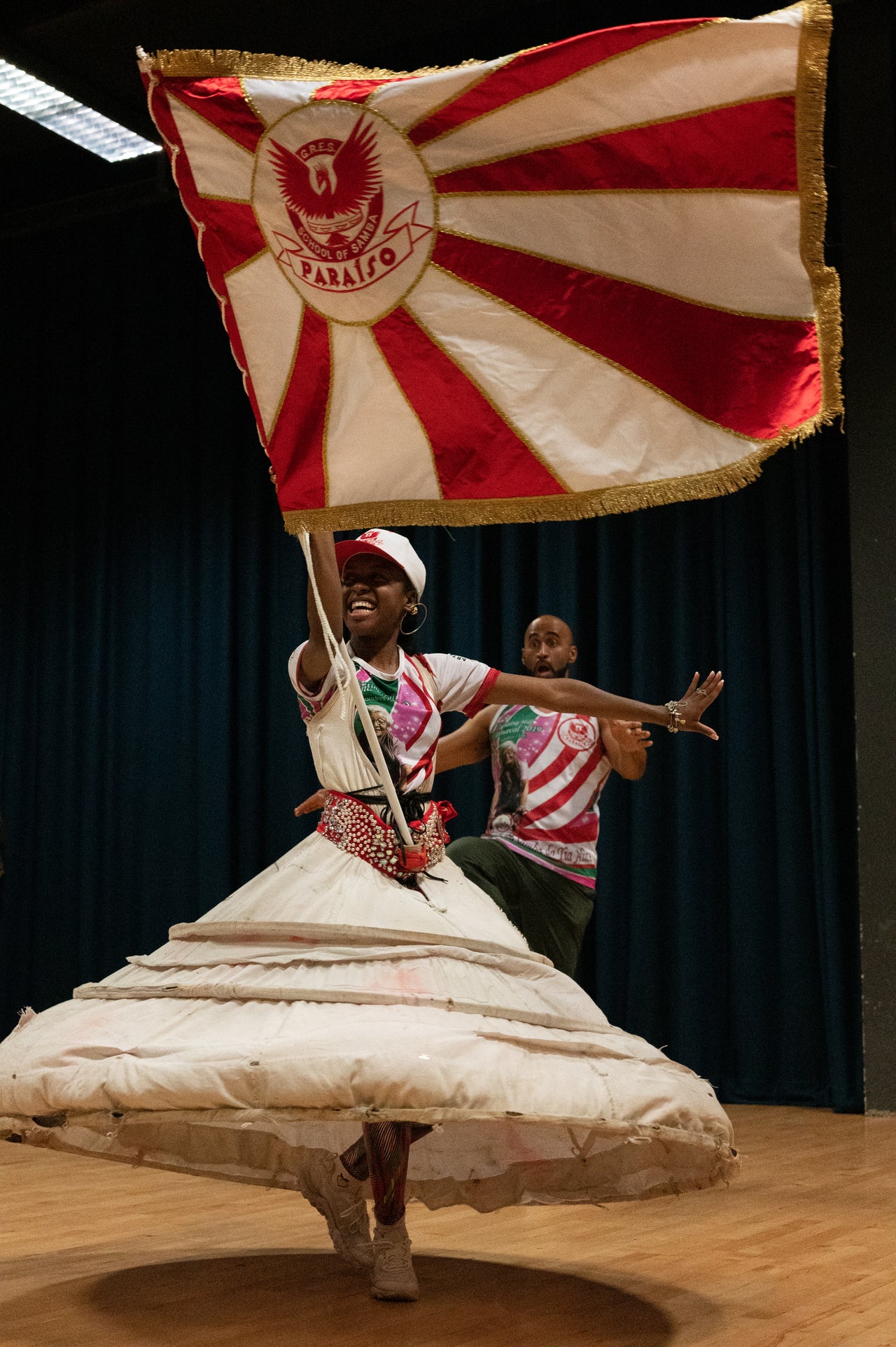 Amber Ogunsanya-William (20) is this year's Porta-Bandeira, meaning Flag Bearer, for the Paraiso School of Samba — a role that is considered royalty in Brazilian culture. She is accompanied by Chirag Goyate, the Mestre Sala, and together they will open and lead Paraiso in this year's Notting Hill Carnival Parade. "This year’s Carnival represents happiness," Ogunsanya-William says. "I haven’t been happy in such a long time. You get a special spiritual energy when you parade, and you really feel the ancestors walking with you."