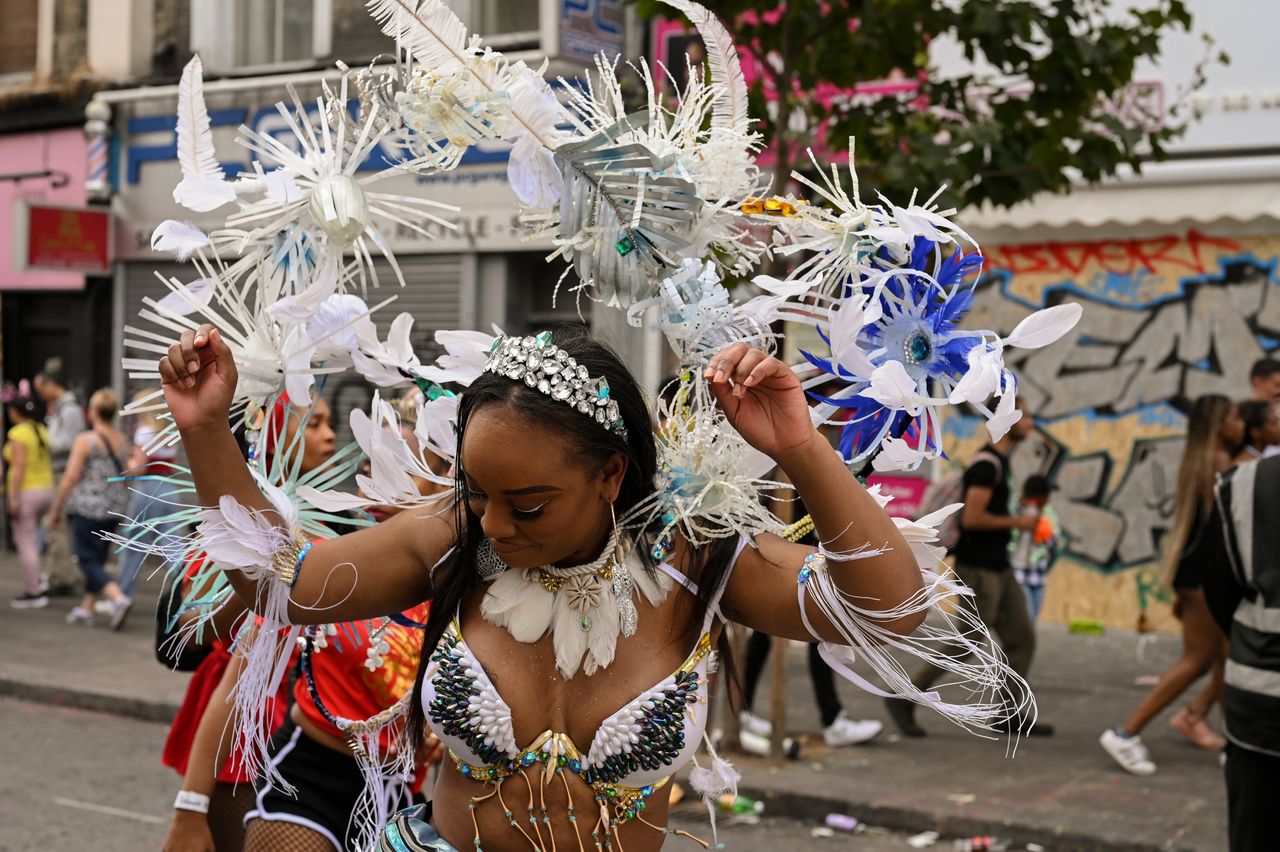 Bianca Wardally participates in the Notting Hill Carnival wearing a Vibrance Mas Band costume designed by Cee Bolakee. The outfit is inspired by the effects of climate change on coral reefs, particularly Bolakee's home island of Mauritius.