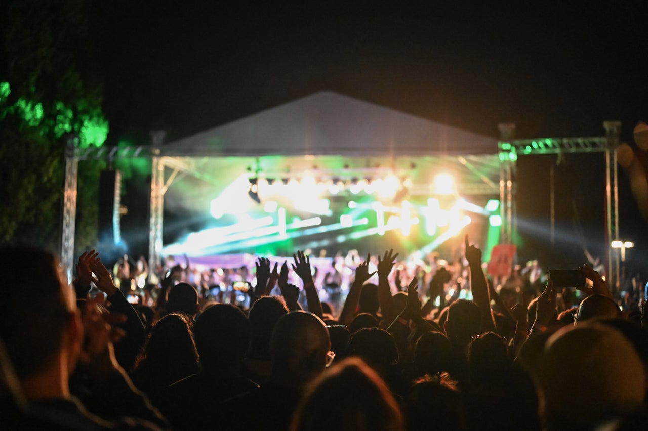 Spectators raise their hands as they watch bands perform at the Panorama Steel Band competition.