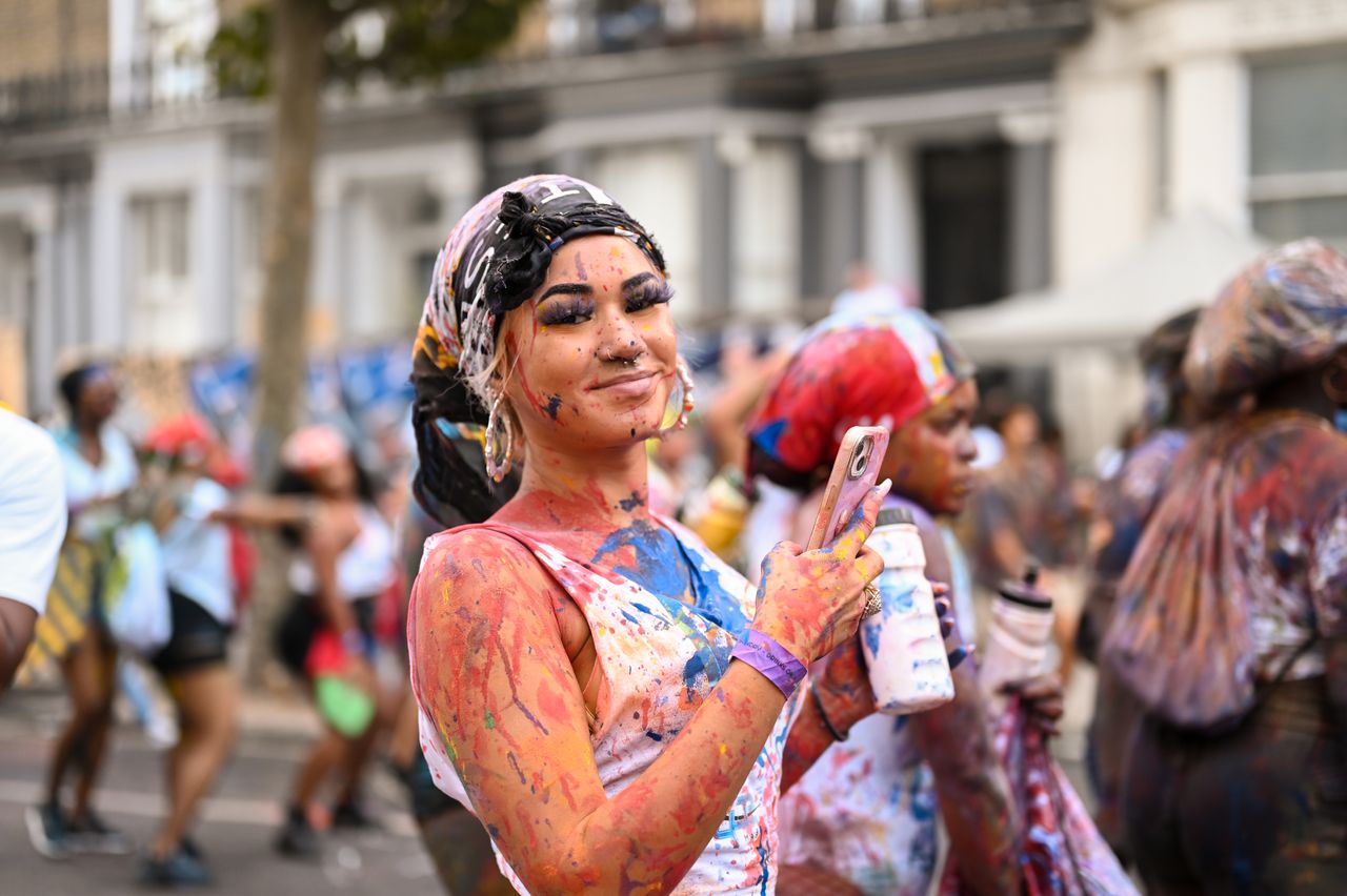 A woman covered in paint and colorful powder participates in Dutty Mas, which takes place on the second day of Notting Hill Carnival and signifies the start of the Carnival parade.