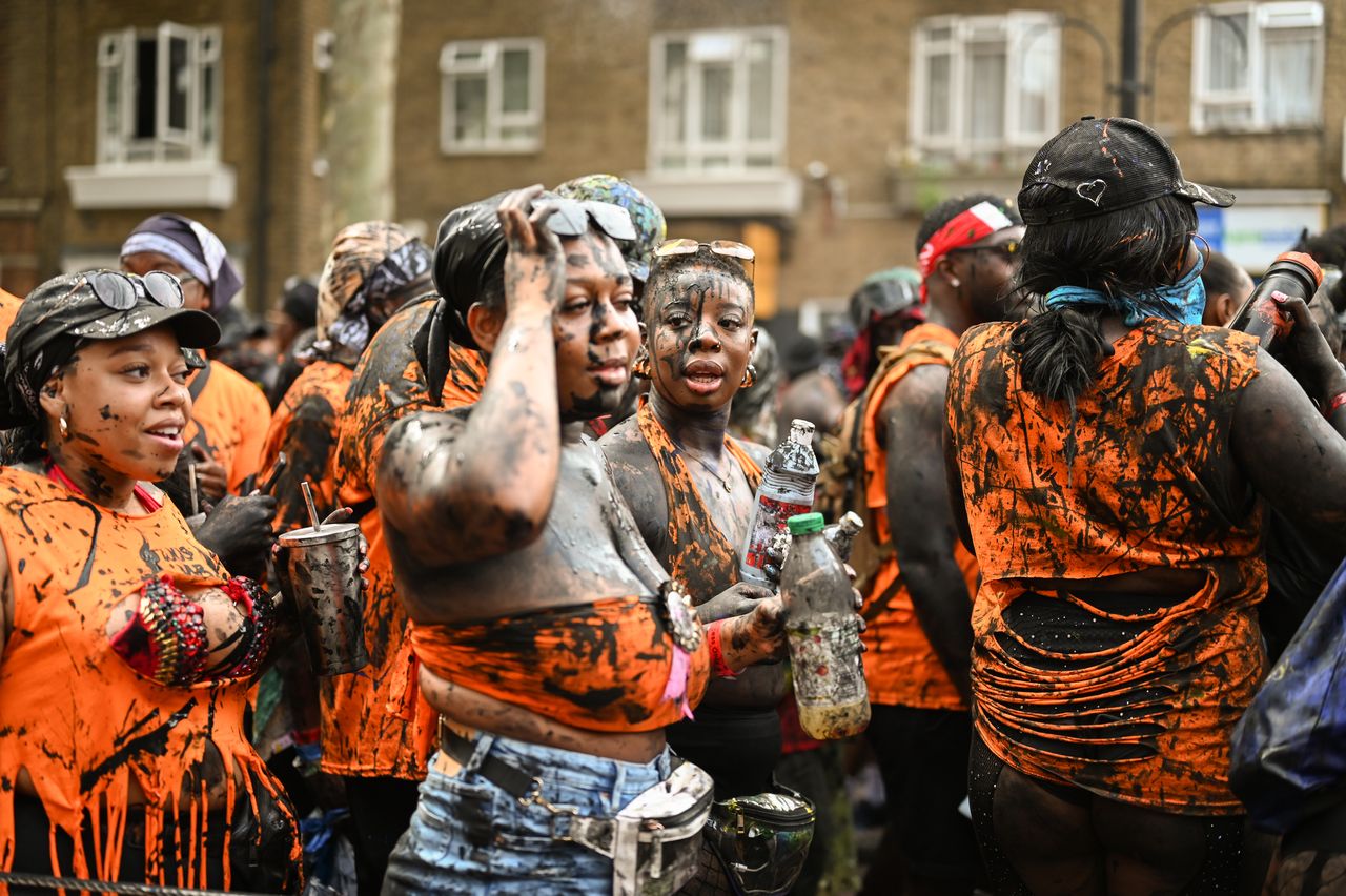 Women covered in black paint attend Dutty Mas.