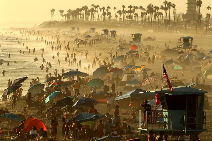 People crowd the beach as fog drifts ashore at sunset in Huntington Beach, California, on Monday.