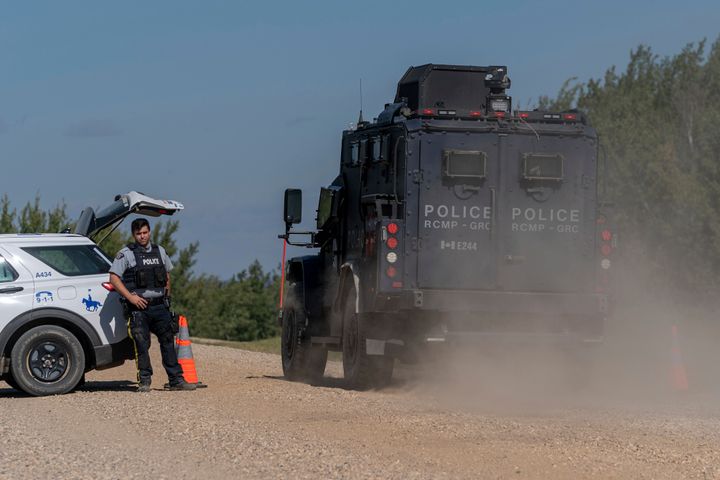 An armored RCMP vehicle, right, drives past a police roadblock set up on the James Smith Cree First Nation reservation in Saskatchewan, Canada, Tuesday, Sept. 6, 2022, as they search for a suspect in a series of stabbings.