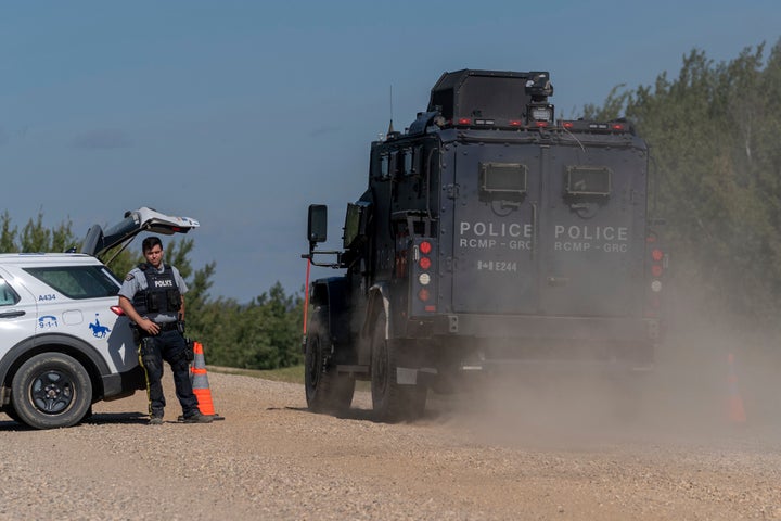 An armored RCMP vehicle, right, drives past a police roadblock set up on the James Smith Cree First Nation reservation in Saskatchewan, Canada, Tuesday, Sept. 6, 2022, as they search for a suspect in a series of stabbings.