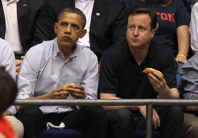 ホットドッグを食べながらバスケットボールを観戦するバラク・オバマ氏と、当時のイギリスの首相デーヴィッド・キャメロン氏（2012年3月13日）