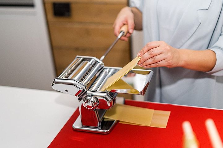 The Imperia pasta maker in action, making wide noodle sheets.