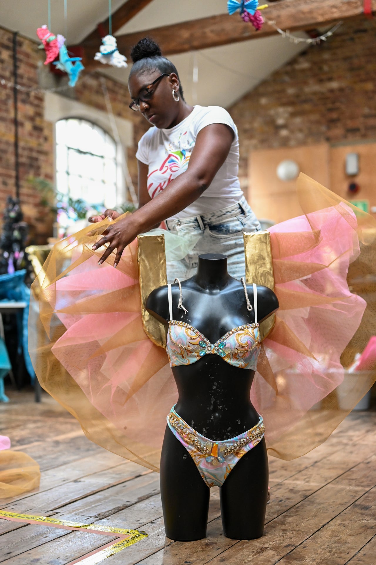 Rishelle, a designer for Funatik's Mas Band, adjusts a costume for her Carnival section, "Cloud Nine." "My design is inspired by the feeling of coming out of lockdown," Rishelle says. "We were stuck, we couldn't see friends, we couldn't go anywhere, and then we came out and we could finally be somewhat normal again, it made me feel like I was on cloud nine."