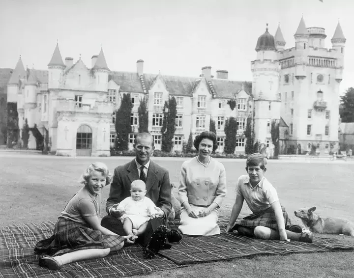 El príncipe Andrés en el regazo del príncipe Felipe de Edimburgo durante un picnic en los terrenos del Castillo de Balmoral. También aparecen la reina Isabel, el príncipe Carlos y la princesa Ana.