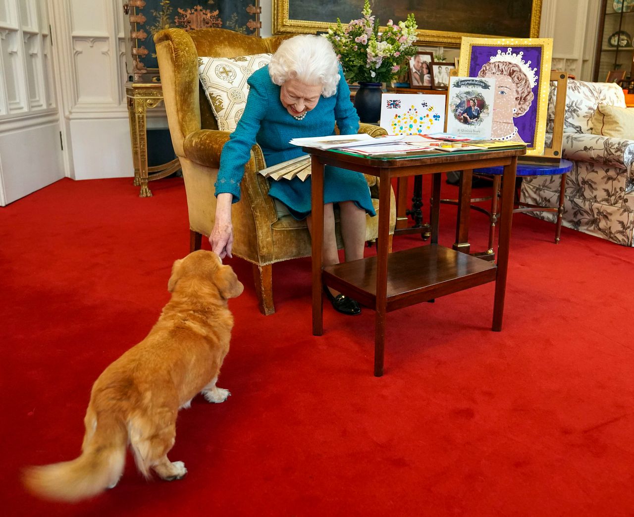 Queen Elizabeth II is joined by one of her dogs, Candy, as she views a display of memorabilia from her Golden and Platinum Jubilees at Windsor Castle on February 4, 2022.
