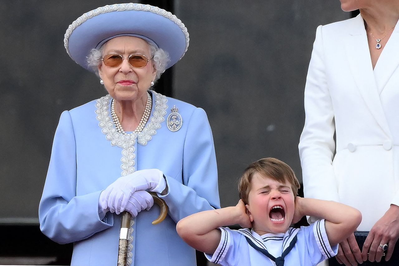 Prince Louis of Cambridge holds his ears as he stands next to Queen Elizabeth II to watch a special flypast from Buckingham Palace balcony following the Queen's Birthday Parade on June 2, 2022.