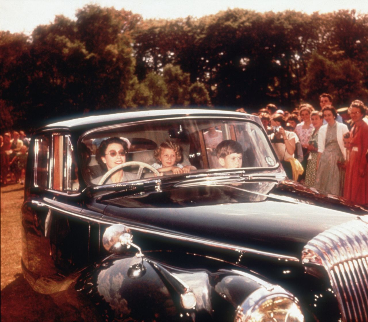 Queen Elizabeth II driving a Daimler saloon car with Prince Charles and Princess Anne as passengers, circa 1957.