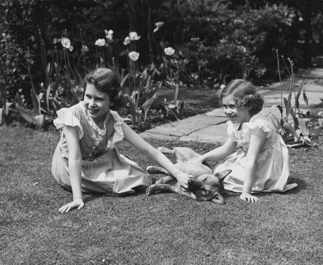Princess Elizabeth and her younger sister, Princess Margaret, petting a corgi in 1936.