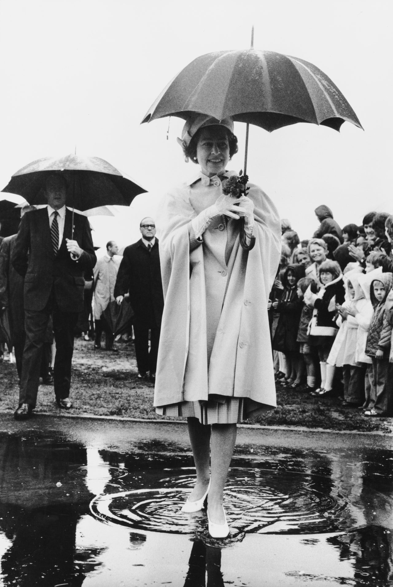 Queen Elizabeth II steps into a puddle during her visit to New Zealand in 1977.