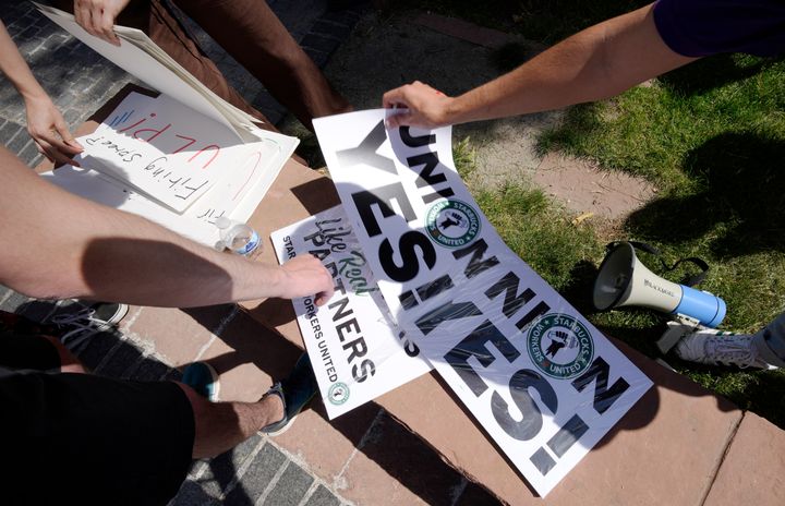 Workers pick up placards during a rally for efforts to unionize Starbucks stores on June 11, 2022, outside the State Capitol in Denver. 