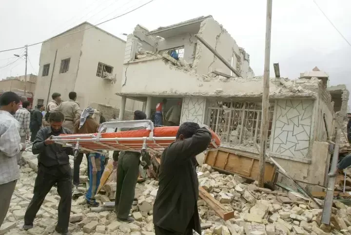 米軍の住宅密集地への空爆で破壊された民家から家財道具を運び出す市民（イラク・バグダッド、2003年3月）
