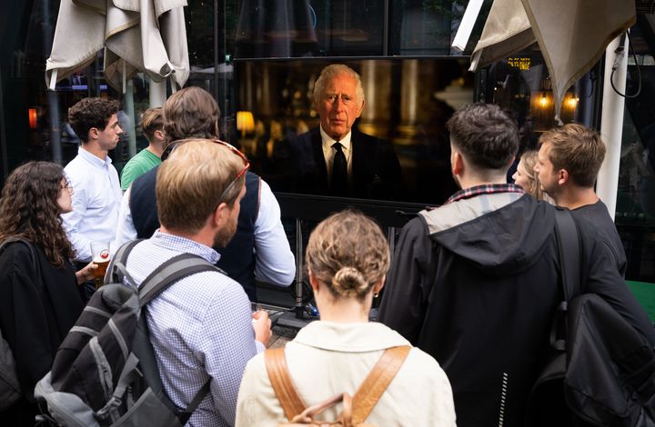 LONDON, ENGLAND - SEPTEMBER 09: Members of the public watch on screens in Victoria as King Charles III addresses the nation for the first time since becoming King, on September 09, 2022 in London, England. Elizabeth Alexandra Mary Windsor was born in Bruton Street, Mayfair, London on 21 April 1926. She married Prince Philip in 1947 and acceded the throne of the United Kingdom and Commonwealth on 6 February 1952 after the death of her Father, King George VI. Queen Elizabeth II died at Balmoral Castle in Scotland on September 8, 2022, and is succeeded by her eldest son, King Charles III.> on September 09, 2022 in London, England. (Photo by Samir Hussein/WireImage)