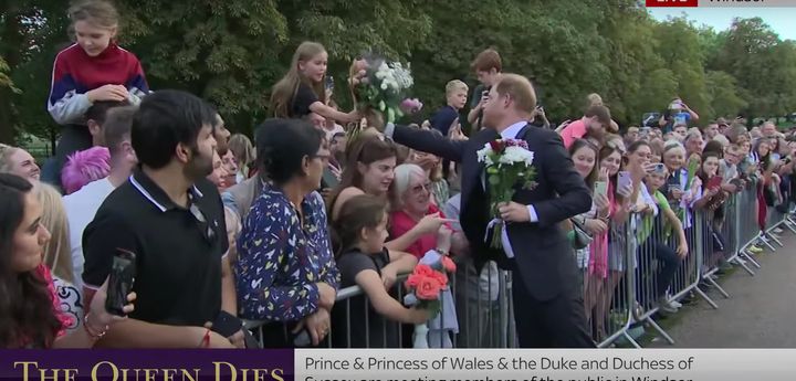 Harry recoge flores de los británicos que han ido a dar apoyo a la Familia Real a las afueras de Widnsor.