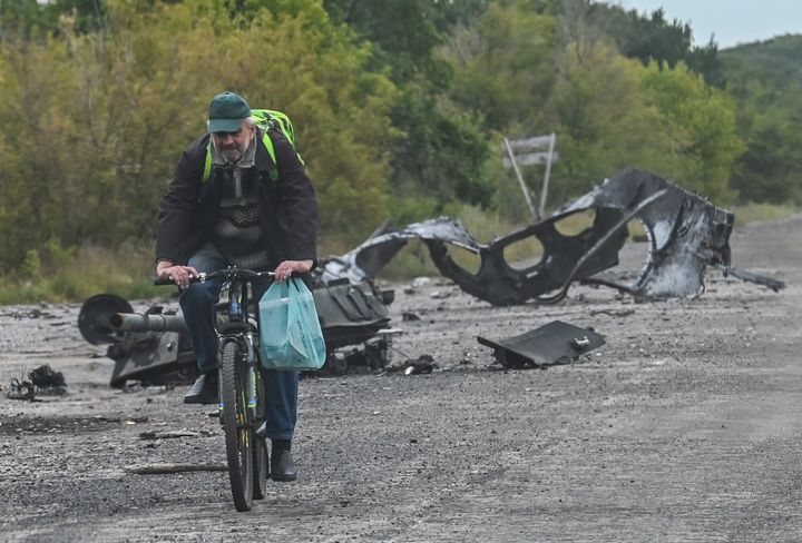 A man cycles past parts of a destroyed armoured vehicle on a road in Balakliya, Kharkiv region. 