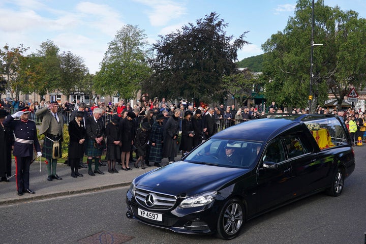 Members of the public line the streets in Ballater, Scotland, as the hearse carrying the coffin of Queen Elizabeth II passes through as it makes its journey to Edinburgh from Balmoral in Scotland, Sunday, Sept. 11, 2022. The Queen's coffin will be transported Sunday on a journey from Balmoral to the Palace of Holyroodhouse in Edinburgh, where it will lie at rest before being moved to London later in the week. (Andrew Milligan/PA via AP)