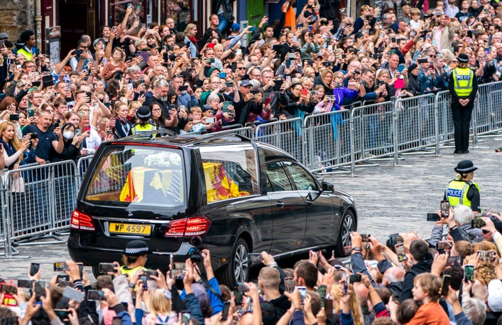 The hearse carrying the coffin of Queen Elizabeth II, draped with the Royal Standard of Scotland, passes the City Chambers on the Royal Mile, Edinburgh, Sunday, Sept. 11, 2022 on the journey from Balmoral to the Palace of Holyroodhouse in Edinburgh, where it will lie in rest for a day. (Jane Barlow/Pool Photo via AP)