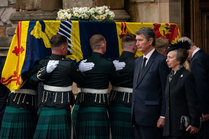 The Princess Royal stands solemnly as the coffin of Queen Elizabeth II, draped with the Royal Standard of Scotland, completes its journey from Balmoral to the Palace of Holyroodhouse in Edinburgh.