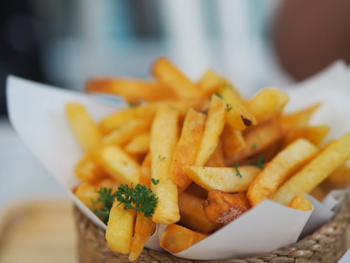 Closeup French fries, Potato chips Yellow crispy fries in wooden basket on white table, snack delicious food