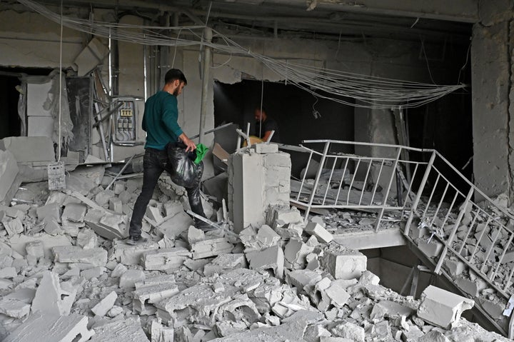 Local residents carry out their belongings from a building partially destroyed by a missile strike in Kharkiv on September 12, 2022.