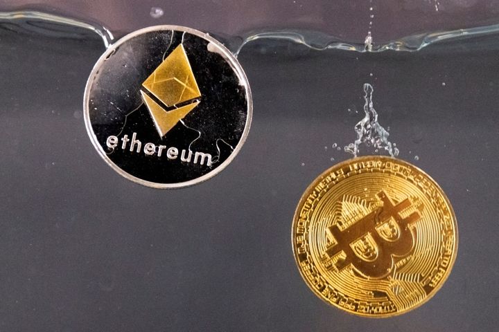 Σε αυτήν την εικόνα, στις 17 Μαΐου 2022, μάρκες αναμνηστικών που αντιπροσωπεύουν το κρυπτονόμισμα Bitcoin και το δίκτυο Ethereum, βυθίζονται - συμβολικά - στο νερό. REUTERS/Dado Ruvic/Illustration