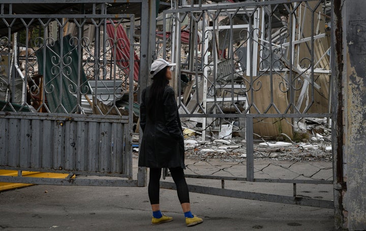 A woman stands in front of the gate of local market with heavily damaged shops after latest Russian rocket attack in Dnipro, Ukraine, on Sept. 12, 2022.