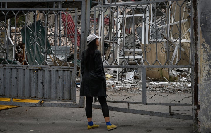 A woman stands in front of the gate of local market with heavily damaged shops after latest Russian rocket attack in Dnipro, Ukraine, on Sept. 12, 2022. 