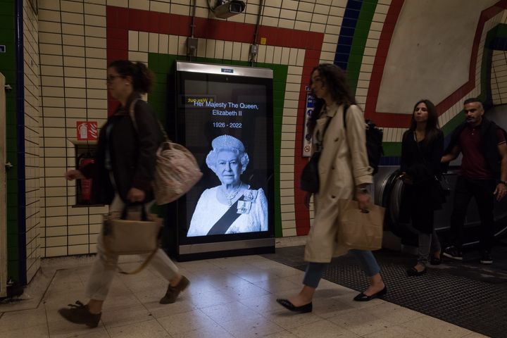 People walk past a digital portrait of Queen Elizabeth II inside an underground station on the second day of national mourning