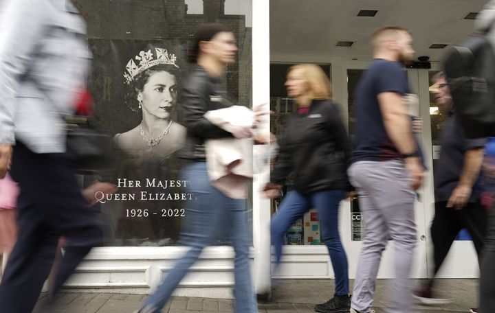 People walk past a picture in the window of WH Smiths in memory of Queen Elizabeth II in Windsor.