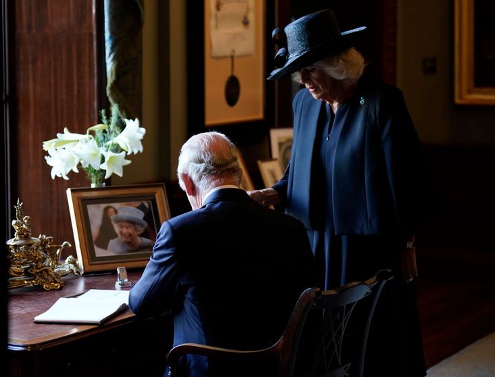King Charles III and Camilla, the Queen Consort, sign the visitors book at Hillsborough Castle, Northern Ireland.