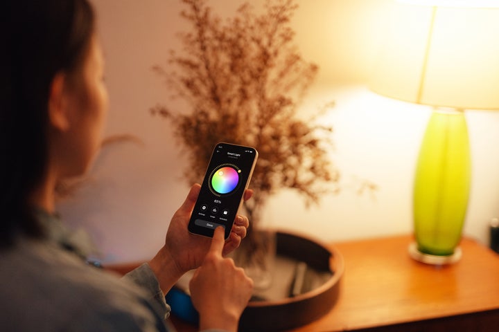 Woman using smartphone to adjust a smart light