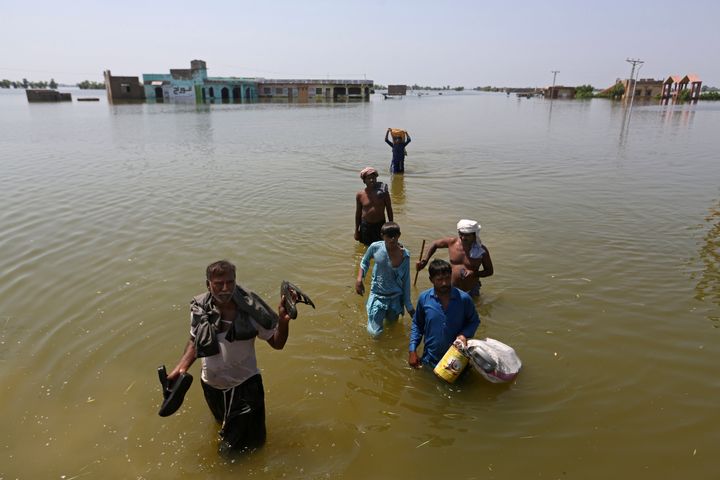 Victims of flooding from monsoon rains carry belongings salvaged from their flooded home in the Dadu district of Sindh Province, of Pakistan, Sept. 9, 2022.