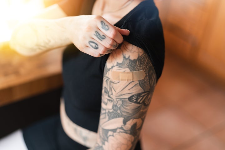 Woman with an adhesive bandage on the shoulder from getting the COVID-19 vaccine shot in the arm.