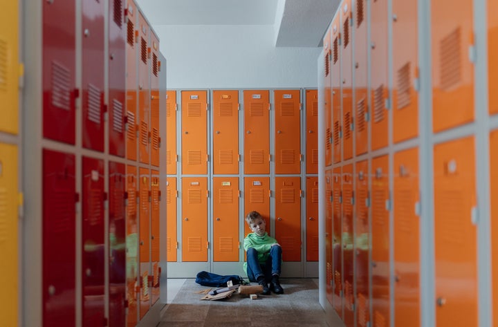 Adolescente triste sentado en las taquillas.