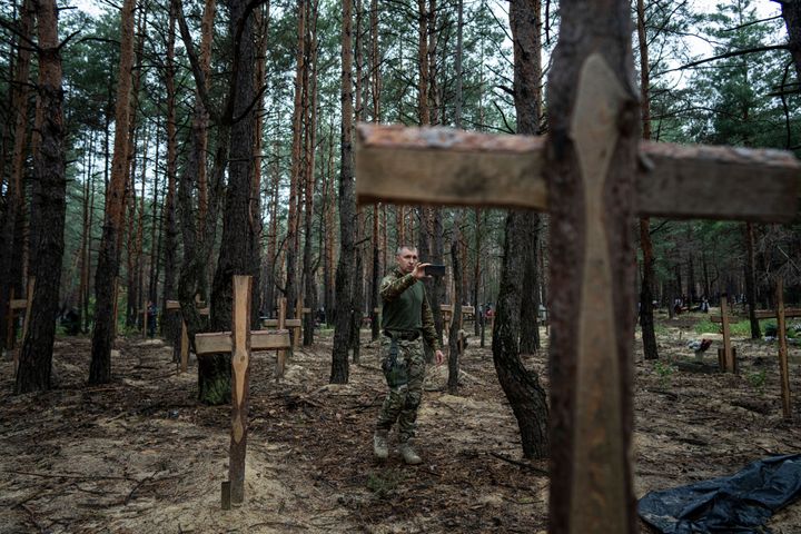 Ο Oleg Kotenko, ο Επίτροπος για Θέματα Αγνοουμένων υπό Ειδικές Περιστάσεις χρησιμοποιεί το smartphone του για να κινηματογραφήσει τον τάφο ενός Ουκρανού στρατιώτη, ο οποίος είχε σκοτωθεί από τις ρωσικές δυνάμεις στην αρχή του πολέμου. Ένας ομαδικός τάφος Ουκρανών στρατιωτών και άγνωστων θαμμένων αμάχων βρέθηκε σε δάσος της πόλης Izium. (AP Photo/Evgeniy Maloletka)