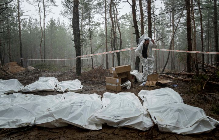 イジューム郊外の森の中で見つかった集団墓地の調査現場。発掘された遺体が袋に収容されている (AP Photo/Evgeniy Maloletka)
