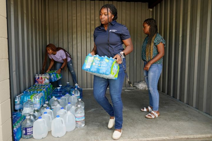 Mississippi Students Water Crisis Advocacy Team members, Jordyn Jackson, 21, left, coordinator Maisie Brown, 20, right, and Mya Grimes, 18, carry out cases of water from their Jackson, Miss., storage locker for home delivery, Sept. 8, 2022. A boil-water advisory has been lifted for Mississippi's capital, and the state will stop handing out free bottled water on Saturday. But the crisis isn't over. Water pressure still hasn't been fully restored in Jackson, and some residents say their tap water still comes out looking dirty and smelling like sewage.(AP Photo/Rogelio V. Solis)