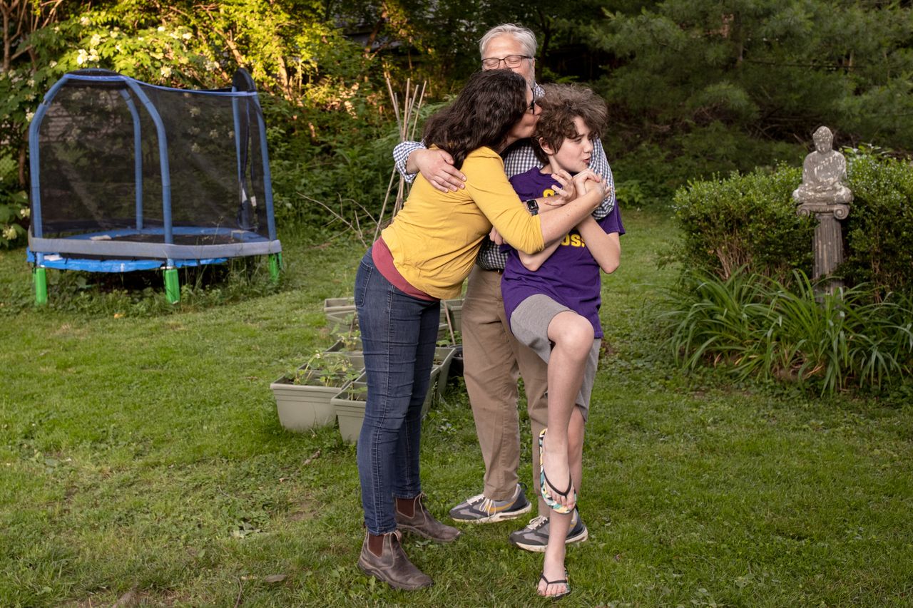 Jennifer Alonzo and Brian Wells wrestle some kisses onto each other and their daughter, Fischer Wells, in their backyard in Louisville.