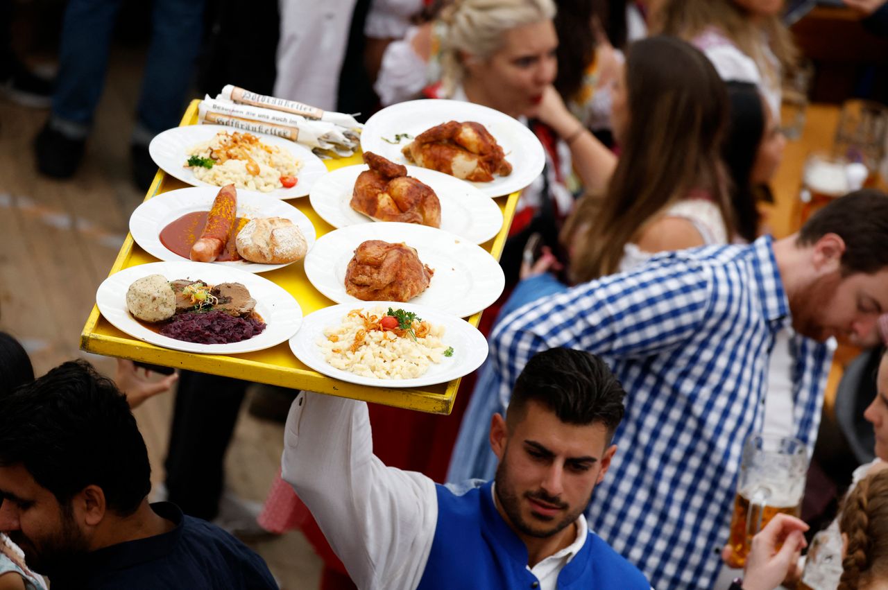 A waiter carries plates with food during the official opening the world's largest beer festival, the 187th Oktoberfest in Munich, Germany, September 17, 2022. REUTERS/Michaela Rehle