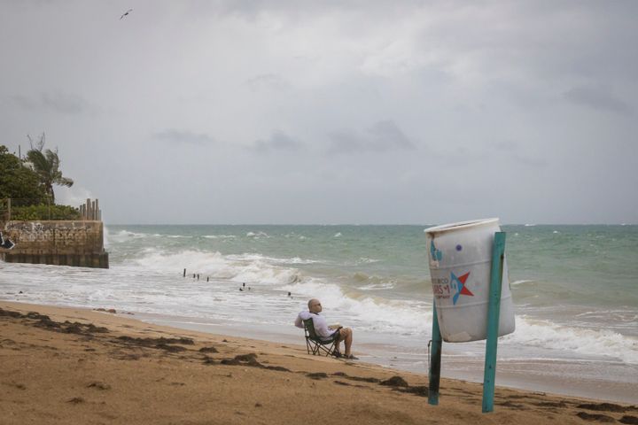 A man sits in front of a beach watching as the waves break before the arrival of Tropical Storm Fiona in San Juan, Puerto Rico, Saturday, Sept. 17, 2022. Fiona was expected to become a hurricane as it neared Puerto Rico on Saturday, threatening to dump up to 20 inches of rain as people braced for potential landslides, severe flooding and power outages. (AP Photo/Alejandro Granadillo)