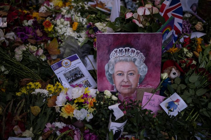 A painting of the Queen Elizabeth II is seen next to flowers at Green Park, near Buckingham Palace, in London, Sunday, Sept. 18, 2022. (AP Photo/Felipe Dana)
