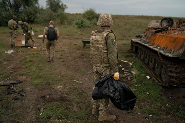 Ένας Ουκρανός στρατιώτης κουβαλά μια τσάντα που περιέχει τα λείψανα ενός Ρώσου στρατιώτη που βρέθηκε μέσα σε άρμα μάχης σε μια περιοχή που ανακτήθηκε κοντά στα σύνορα με τη Ρωσία στην περιοχή Χάρκοβο, Ουκρανία, Σάββατο, Σεπτέμβριο. 17, 2022. (AP Photo / Leo Correa)