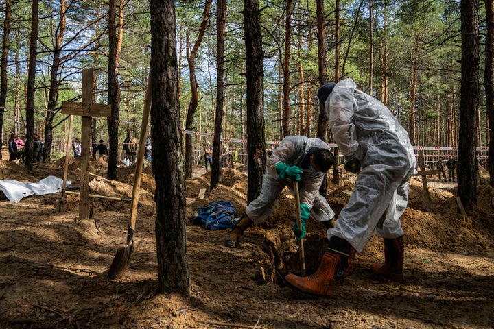 Emergency workers dig into the grave of a civilian during an exhumation in the recently retaken area of Izium, Ukraine, Saturday, Sept. 17, 2022. Ukrainian authorities discovered a mass burial site near the recaptured city of Izium that contained hundreds of graves. It was not clear who was buried in many of the plots or how all of them died, though witnesses and a Ukrainian investigator said some were shot and others were killed by artillery fire, mines or airstrikes.